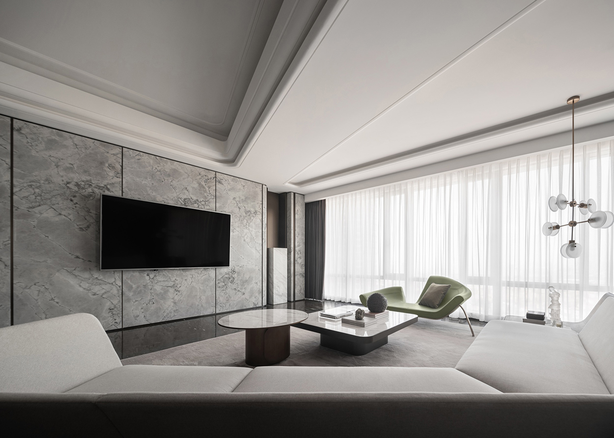 Contemporary living room with a marble feature wall and wall‑mounted TV, light‑coloured sofa, round and rectangular coffee tables, green lounge chairs, and floor‑to‑ceiling sheer curtains.