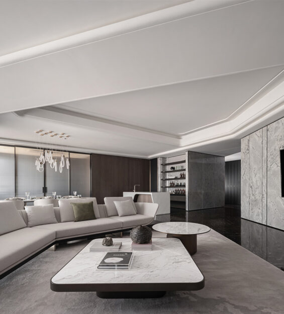 Contemporary living room with a marble feature wall and wall‑mounted TV, light‑coloured sofa, round and rectangular coffee tables, green lounge chairs, and floor‑to‑ceiling sheer curtains.